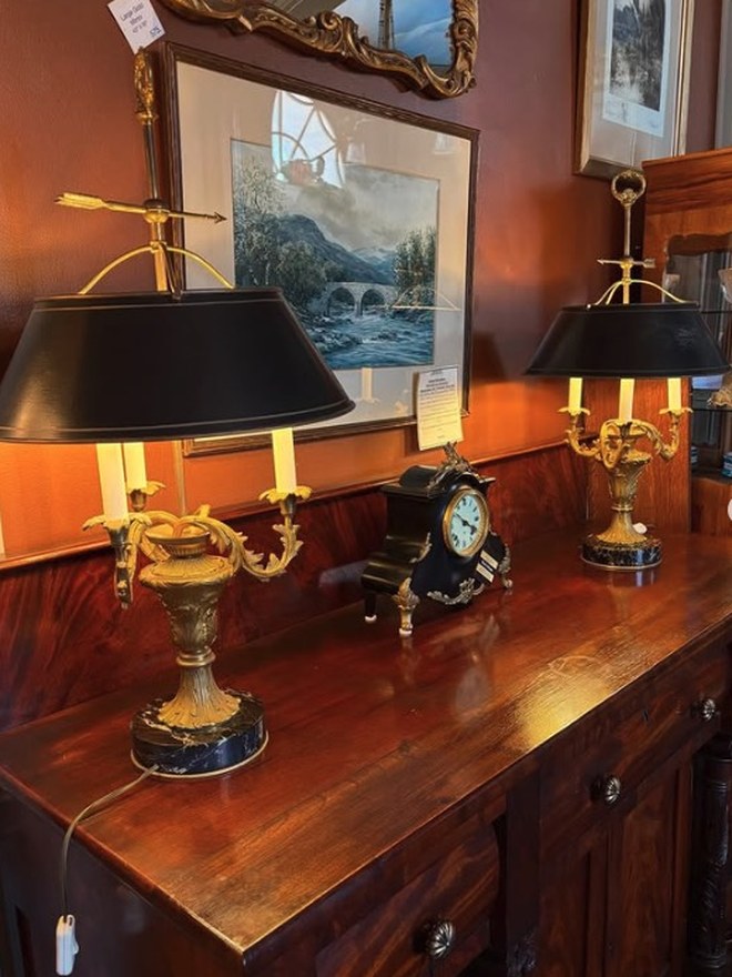 Pair of gilt-brass bouillotte lamps with black tole shades and candle arms, on an Empire mahogany sideboard.