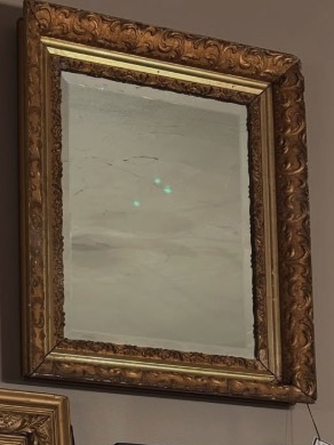 Rectangular mirror in a deep giltwood frame carved with foliate scrollwork on the outer molding and a plain gilt inner lip, the plate lightly foxed.