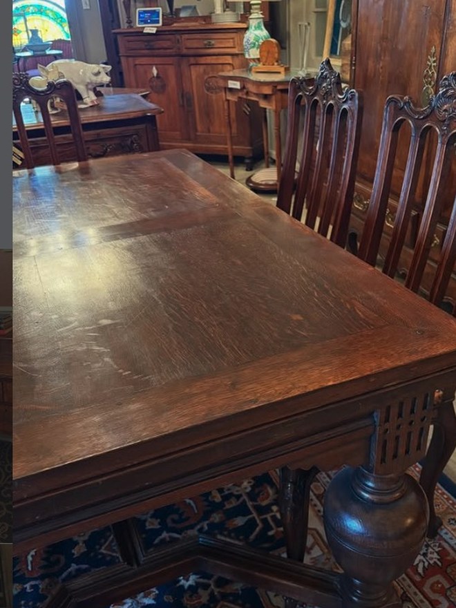 Dutch oak refectory table with heavy bulbous turned legs, drawleaf ends, and a row of carved high-back chairs behind.
