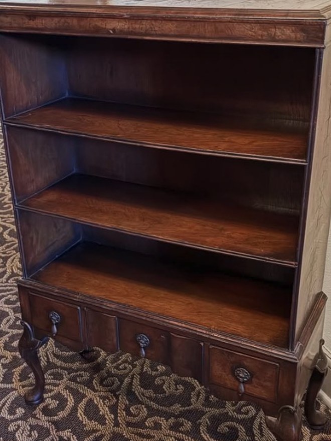 Open walnut bookcase on stand with three graduated shelves over three drawers, raised on Queen Anne cabriole legs.